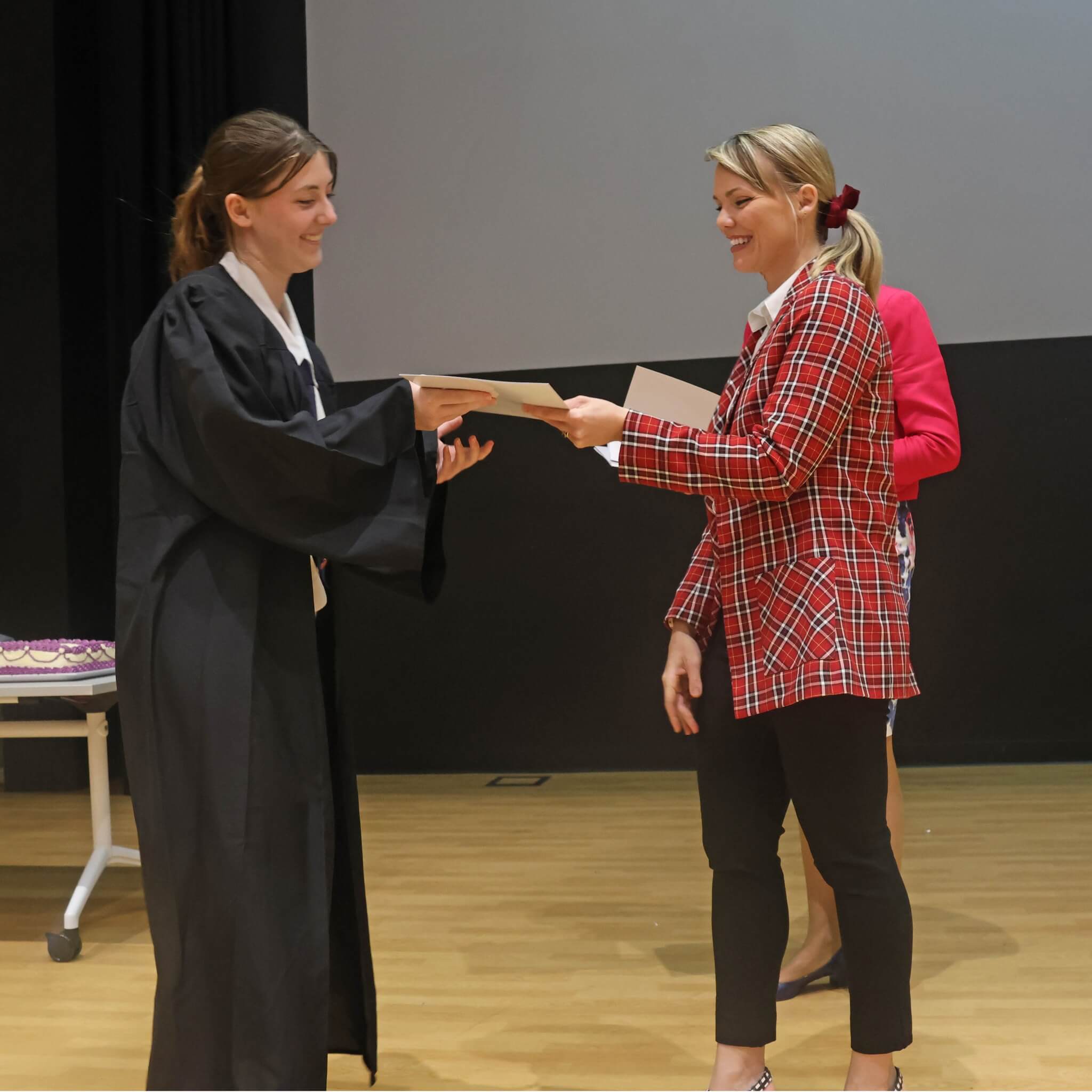 Kate Taylor handing graduation certificate to student